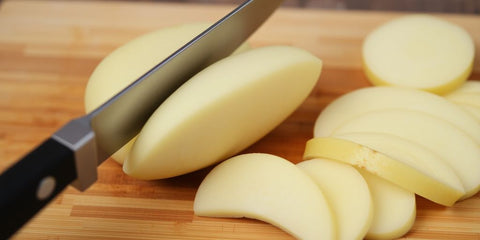 Knife slicing potato on cutting board